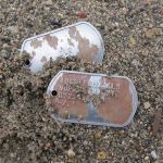 Rusty Steel Dog Tag with random rust spotting in sand