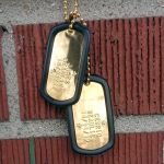 Shiny Gold Plated Dog Tags on Brick Wall